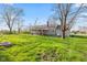 Rear yard of home showing lawn, patio, brick chimney and mature trees at 7008 E Jackson St, Muncie, IN 47303