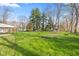 Expansive backyard with lush green grass, mature trees, and a carport at 7008 E Jackson St, Muncie, IN 47303