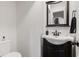 Powder room with dark wood vanity, a decorative mirror, and low flow toilet at 7008 E Jackson St, Muncie, IN 47303