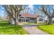 Charming single-story home with a covered porch, stone facade, and mature trees at 7008 E Jackson St, Muncie, IN 47303