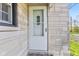 A white front door with a storm door is surrounded by stone accents and a small front window at 7008 E Jackson St, Muncie, IN 47303