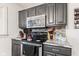 This kitchen features stainless steel appliances, gray cabinets, and stone countertops at 7008 E Jackson St, Muncie, IN 47303