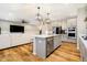 Open-concept kitchen with stainless appliances, white countertops and island with barstool seating, adjacent to living room at 7158 Sugar Maple Ln, Brownsburg, IN 46112