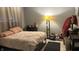 Cozy bedroom with a neutral pink bedspread, dark wood dresser, and a floor lamp at 8006 Sunfield Ct, Indianapolis, IN 46214