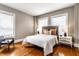 Bedroom with hardwood floors, neutral walls, and a comfortable queen-sized bed next to bright windows at 801 N Pennsylvania St # Apt D, Indianapolis, IN 46204
