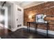 Hallway with brick accent wall, wood floors, table with lamp, and doorway at 801 N Pennsylvania St # Apt D, Indianapolis, IN 46204