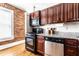 Well-lit kitchen with stainless steel appliances, dark wood cabinets, granite countertops, and exposed brick accents at 801 N Pennsylvania St # Apt D, Indianapolis, IN 46204