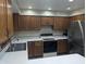 Well-lit kitchen featuring stainless steel refrigerator, an oven, and wooden cabinets at 8017 Dogwood Ct, Plainfield, IN 46168