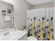 Neutral bathroom featuring a shower with a floral curtain, sink, and framed artwork at 8442 Averly Park Dr, Indianapolis, IN 46237