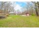 Expansive backyard with creek, wooden bridge, green home, and red outbuilding at 8503 Bean Blossom Rd, Trafalgar, IN 46181