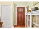 Close up of a brown front door with glass panel next to a white bookshelf and coat closet at 8503 Bean Blossom Rd, Trafalgar, IN 46181