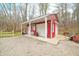 Red outbuilding with white trim, a bench, and gravel and concrete landscaping at 8503 Bean Blossom Rd, Trafalgar, IN 46181