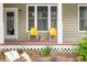 Covered porch with two yellow chairs and decorative greenery and mulch at 8503 Bean Blossom Rd, Trafalgar, IN 46181