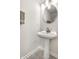Bathroom featuring a pedestal sink with round mirror, modern lighting, and neutral walls at 9338 Eden Woods Ct, Indianapolis, IN 46260