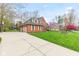 Well-manicured lawn and driveway leading to a grand two-story brick home with mature trees at 945 Baywood Ct, Columbus, IN 47201