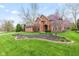 Beautiful brick home featuring a lush green lawn and mature trees under a blue sky at 945 Baywood Ct, Columbus, IN 47201