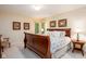 Spacious bedroom with framed art, carpeted floors, and a large wooden sleigh bed with floral comforter at 9838 Gulfstream Ct, Fishers, IN 46037