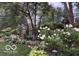 Beautifully landscaped backyard with lush greenery, flowering plants, and a charming garden setting at 10605 Winterwood, Carmel, IN 46032