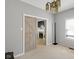Open bedroom with barn door to the left offers neutral paint, carpeted floors, and a view into a living space at 11347 Whitewater Way, Fishers, IN 46037