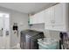 Well-equipped laundry room with tile flooring, white cabinets, and modern black washer and dryer at 11347 Whitewater Way, Fishers, IN 46037