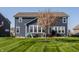 Back exterior showcases a home's blue siding, lawn, and patio with outdoor furniture at 11880 Whisper Ridge Dr, Noblesville, IN 46060