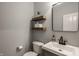 Modern powder room with floating wood shelves, a decorative mirror and grey color palette creates a clean aesthetic at 11880 Whisper Ridge Dr, Noblesville, IN 46060