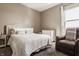 Bright bedroom showcasing a neutral color scheme, a cushioned headboard, and a comfortable leather chair at 11880 Whisper Ridge Dr, Noblesville, IN 46060