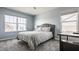 Comfortable bedroom with large windows, a gray upholstered bed, and neutral gray walls and carpet at 11880 Whisper Ridge Dr, Noblesville, IN 46060