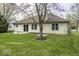 Landscaped backyard featuring a well-maintained lawn, patio, mature trees, and an inviting exterior view of the home at 12249 E Harvest Glen Dr, Cumberland, IN 46229