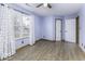 Light-filled bedroom featuring a ceiling fan, wood-look floors, two windows and two doors at 12249 E Harvest Glen Dr, Cumberland, IN 46229