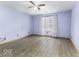 Spacious bedroom with light blue walls, wood-look flooring, a ceiling fan and a window with patterned curtains at 12249 E Harvest Glen Dr, Cumberland, IN 46229