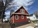 Side view of a red two-story home with a gabled roof, black foundation, and landscaped yard at 128 W Walnut St, Lebanon, IN 46052