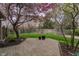Brick patio overlooks a well-maintained backyard with mature trees, flowering shrubs, and a fenced perimeter at 13797 Mill Stream Ct, Carmel, IN 46032