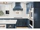 Close up of gourmet kitchen with white backsplash, blue cabinets, and stainless-steel appliances at 14872 Autumn View Way, Fishers, IN 46037
