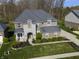 Aerial view of a brick and stone home with an attached garage, long driveway, and green lawn at 2798 W High Grove Cir, Zionsville, IN 46077