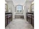 A stunning bathroom with dual sinks, dark wood cabinets, and a separate tub under an arched window at 2798 W High Grove Cir, Zionsville, IN 46077