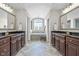 A stunning bathroom with dual sinks, dark wood cabinets, and a separate tub under an arched window at 2798 W High Grove Cir, Zionsville, IN 46077