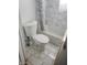 A bathroom featuring a white toilet, marble-look wall tiles, and a shower-tub combination at 2801 Brouse Ave, Indianapolis, IN 46218