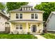 Charming two-story yellow home featuring a welcoming front porch and well-manicured lawn at 3133 Ruckle St, Indianapolis, IN 46205