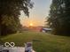 A serene backyard featuring a vast green lawn leading to trees, illuminated by a sunset at 3718 S County Road 101 E, Clayton, IN 46118