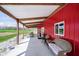 Covered porch featuring outdoor furniture on bright red outbuilding on land with mature trees at 3718 S County Road 101 E, Clayton, IN 46118
