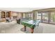 Spacious game room featuring a brick fireplace and sliding doors with serene lake views at 3748 Bay Rd S Dr, Indianapolis, IN 46240