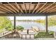 Covered patio space with serene views of the lake and dock, complete with garden beds and an owl statue accent at 3748 Bay Rd S Dr, Indianapolis, IN 46240
