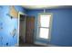 Blue bedroom with peeling paint, closet and bright window at 437 Jefferson Ave, Indianapolis, IN 46201