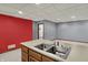 Basement kitchenette sink island with a partial view of the space and bright red wall at 4606 Sundance Trl, Indianapolis, IN 46239
