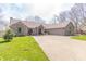 Charming brick home with well-manicured lawn, mature trees, and long driveway leading to an attached garage at 5875 Annanhill Ct, Avon, IN 46123