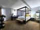 Spacious bedroom with a four-poster bed, bench, carpet and natural light at 6723 Balmoral Rd, Indianapolis, IN 46241