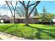 Charming brick home with attached garage and a well-manicured lawn, shaded by mature trees on a sunny day at 6723 Balmoral Rd, Indianapolis, IN 46241