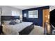 Stylish main bedroom with a striking navy accent wall and ample natural light streaming through the windows at 6826 Hague Rd, Indianapolis, IN 46256