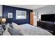 Beautiful main bedroom with a navy accent wall, dresser with television, and light-filled windows at 6826 Hague Rd, Indianapolis, IN 46256
